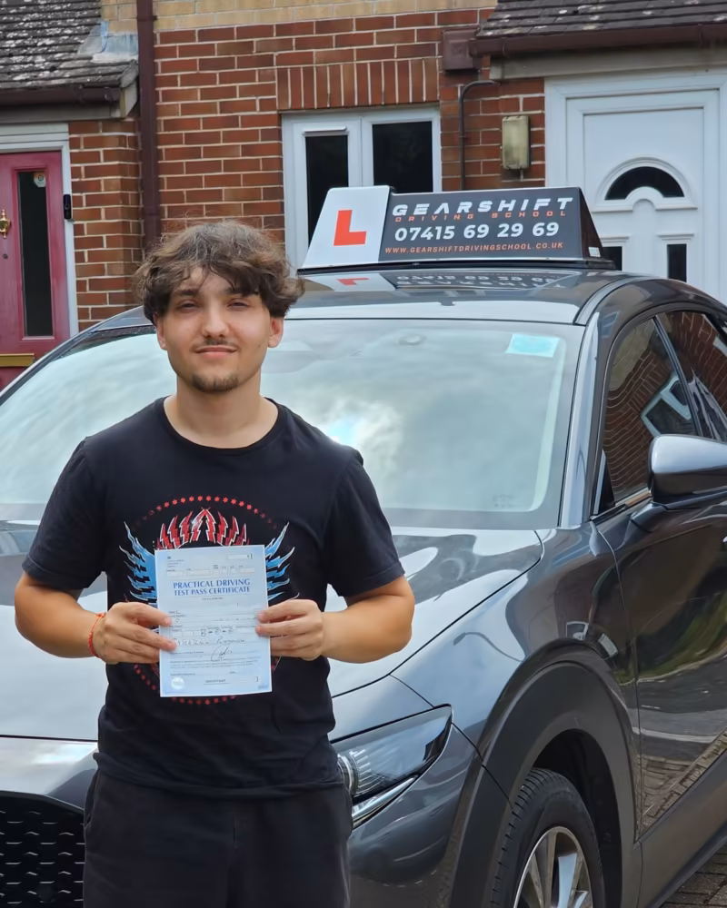 Learner holding their driving test pass certificate next to the Gearshift Driving School car