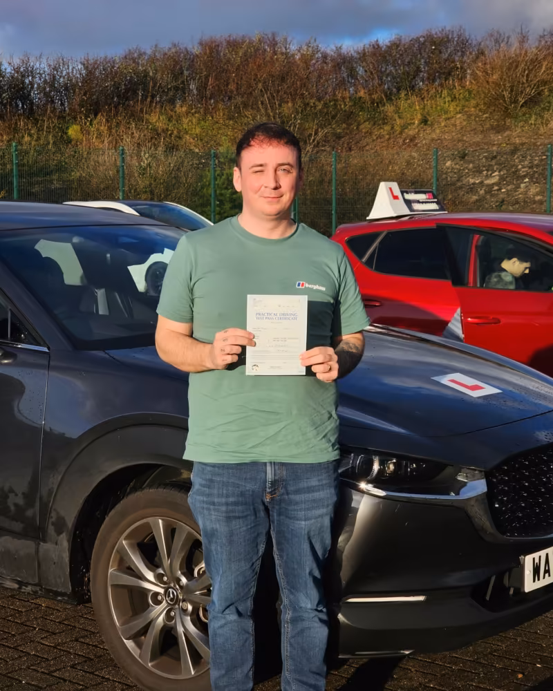 Learner holding their driving test pass certificate next to the Gearshift Driving School car
