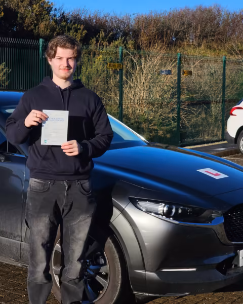 Learner holding their driving test pass certificate next to the Gearshift Driving School car