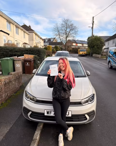 Learner holding their driving test pass certificate next to the Gearshift Driving School car